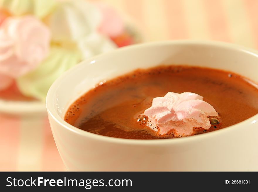 Close up image of a cup with hot chocolate and meringue cookies