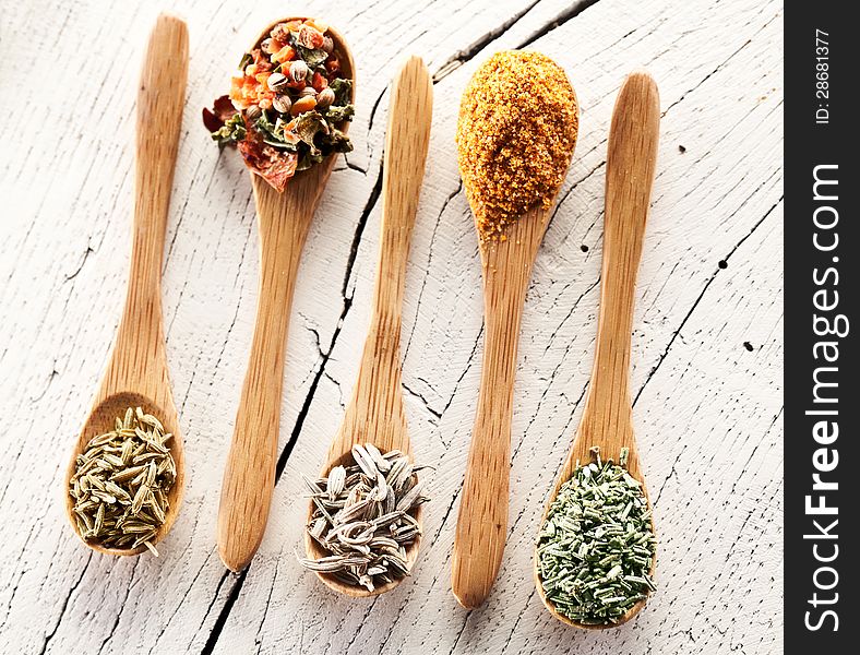 Variety of spices in the spoons on an white old wooden table. Variety of spices in the spoons on an white old wooden table.