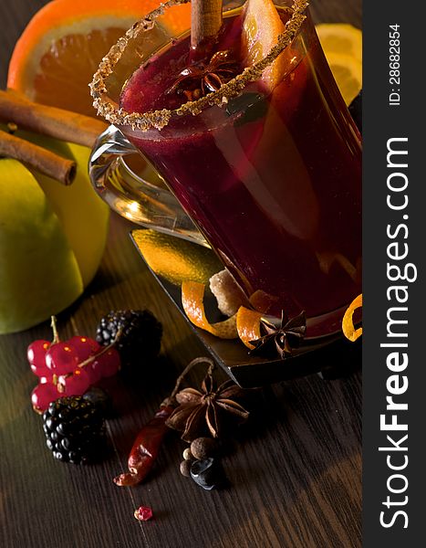 Glass of Mulled Wine with Cinnamon Stick, Slice of Orange and Anise Star closeup on Dark Wood background with Fruits and Spices. Glass of Mulled Wine with Cinnamon Stick, Slice of Orange and Anise Star closeup on Dark Wood background with Fruits and Spices