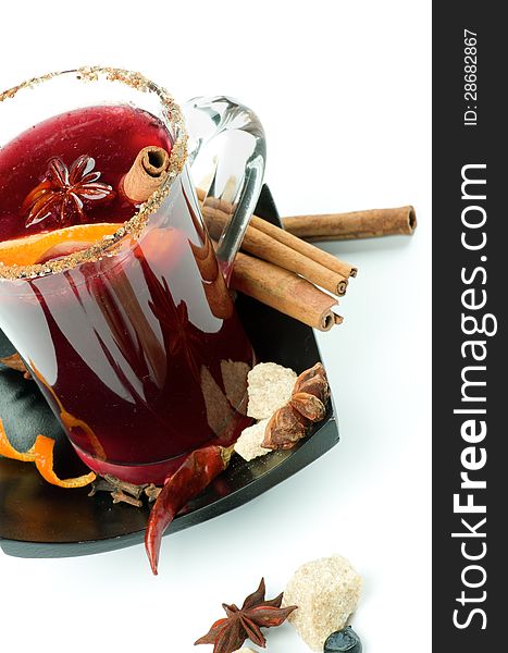 Glass of Mulled Wine with Cinnamon Stick, Slice of Orange, Anise Star and Spices on Black Saucer closeup on white background. Glass of Mulled Wine with Cinnamon Stick, Slice of Orange, Anise Star and Spices on Black Saucer closeup on white background