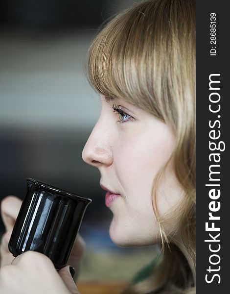 Portrait of a young woman staring straight ahead into the camera holding a cup of coffee. Portrait of a young woman staring straight ahead into the camera holding a cup of coffee.