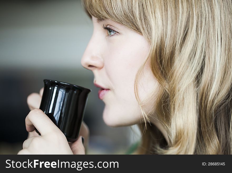 Portrait of a young woman staring straight ahead into the camera holding a cup of coffee. Portrait of a young woman staring straight ahead into the camera holding a cup of coffee.