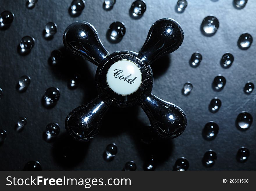 Old faucet on dark background with drops of water