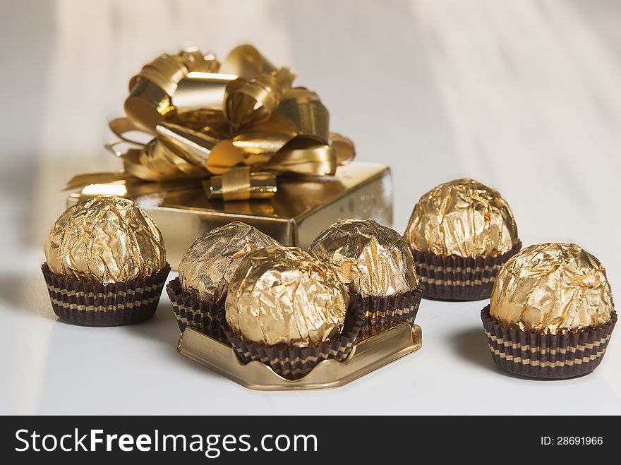 Candy in golden foil over white background