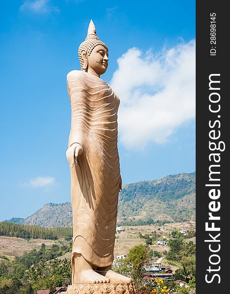 Huge buddha statue with sky background standing on a mountain