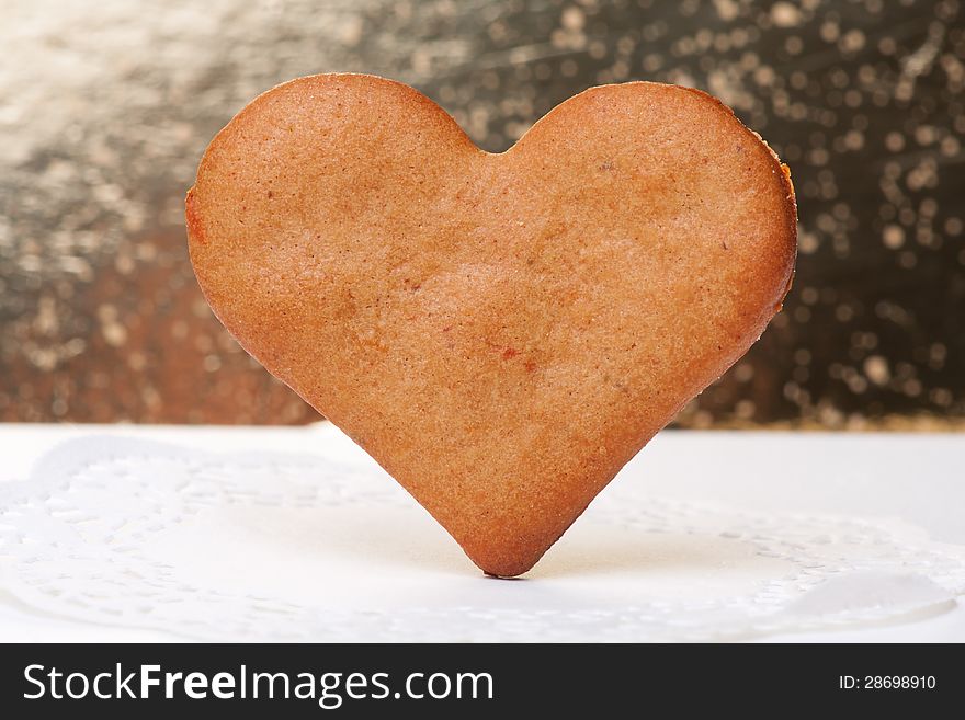 Heart-shaped gingerbread cookie close-up on a golden background