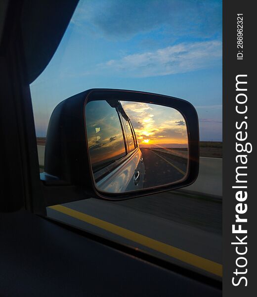 Reflection of the sunset in the rearview mirror of a car