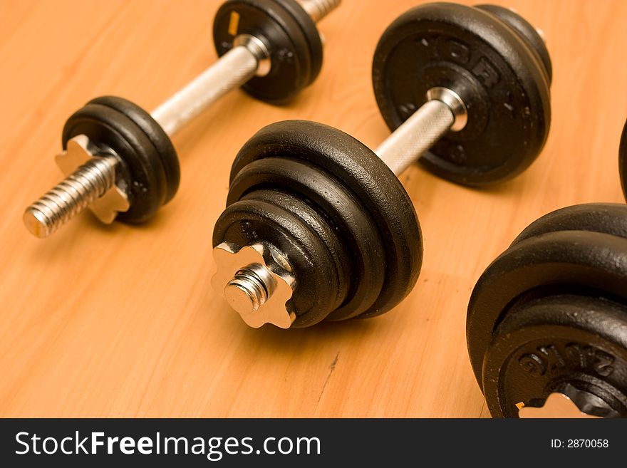 Black barbells on wooded floor. Black barbells on wooded floor.