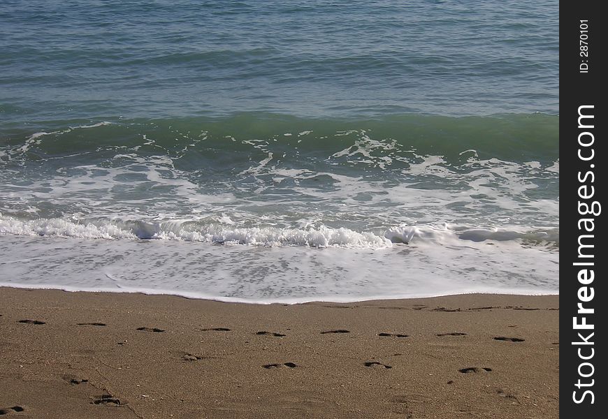 Small waves breaking on the sea shore sand