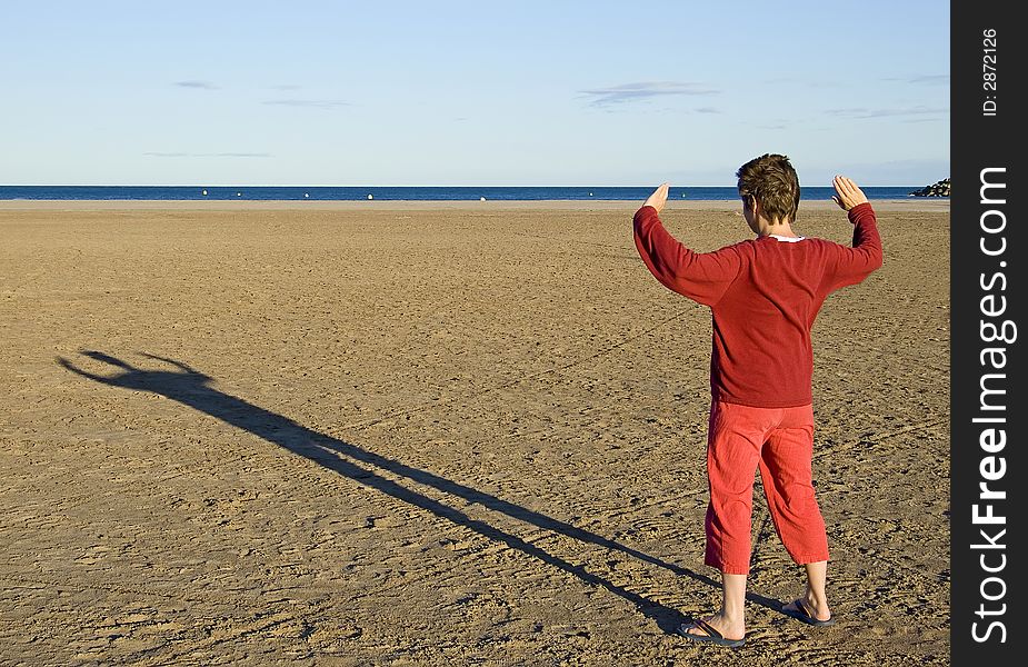 Woman in red clothes making a shadow at sunset on the beach. Woman in red clothes making a shadow at sunset on the beach