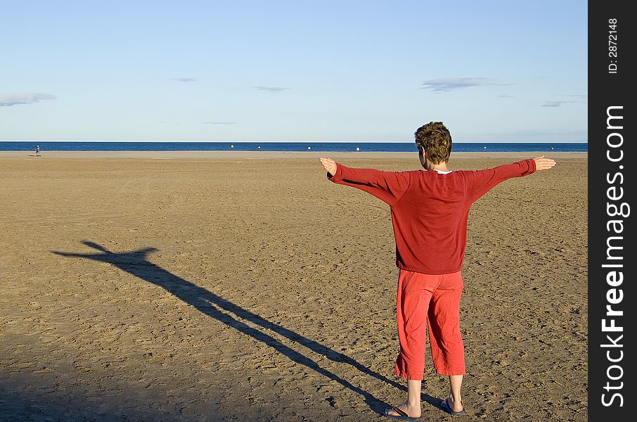 Woman in red clothes making a shadow at sunset on the beach. Woman in red clothes making a shadow at sunset on the beach