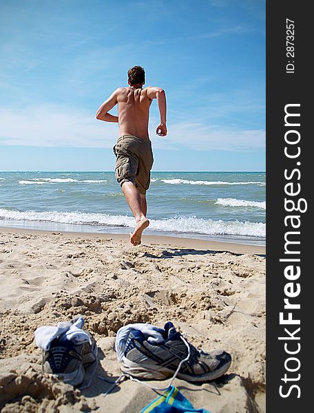 A boy teen runs towards the ocean. A boy teen runs towards the ocean