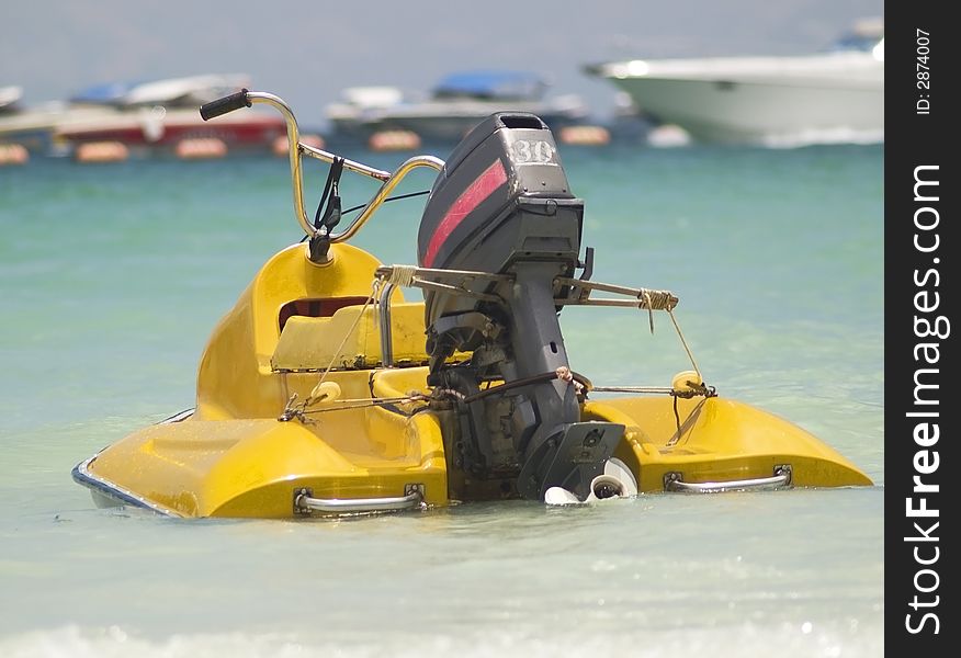 Old style water scooter withoutboard engine. Out of focus boats in the background