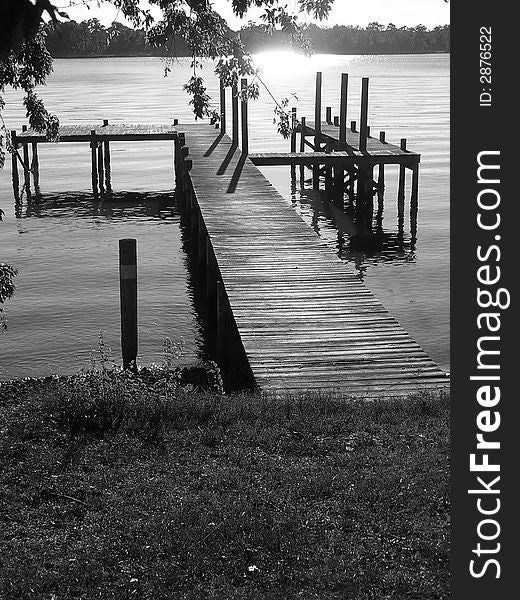 A long fishing pier with the sun reflecting off the water.