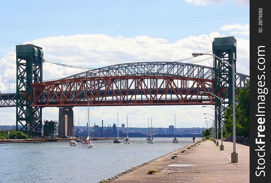 An lifted up lift bridge over the canal to the harbor of Hamilton with sparkling water waves and several small sailboats.