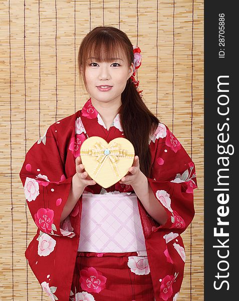 Young asian woman in traditional clothes of kimono, holding a gift box. Young asian woman in traditional clothes of kimono, holding a gift box