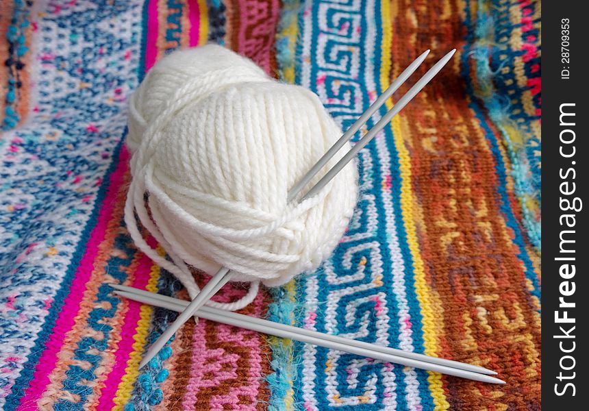 Tangle of white yarn with the knitting needles on the knitted  patterned fabric. Tangle of white yarn with the knitting needles on the knitted  patterned fabric.