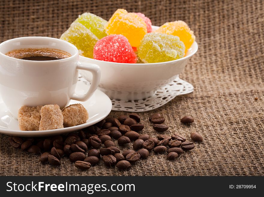 Cup of coffee, grains, dessert on burlap background. Cup of coffee, grains, dessert on burlap background