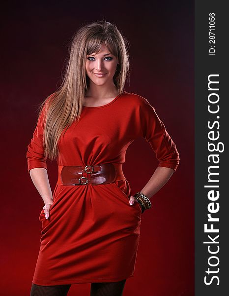 Beautiful young woman in red dress on a dark red background