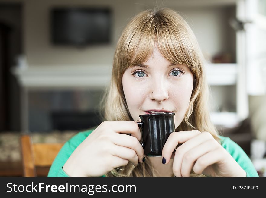 Pretty young blonde woman drinking her morning coffee. Pretty young blonde woman drinking her morning coffee.