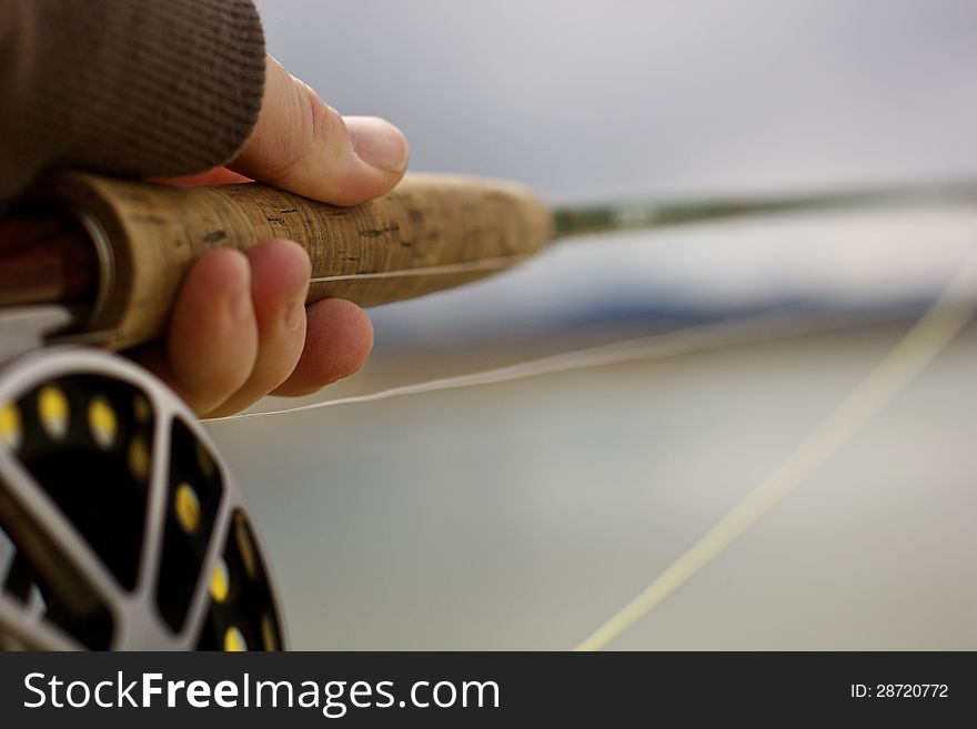 A man holding onto a fly rod and reel. A man holding onto a fly rod and reel.