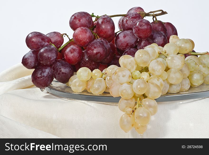 On a large glass dish are ripe grapes: red and white. On a large glass dish are ripe grapes: red and white.