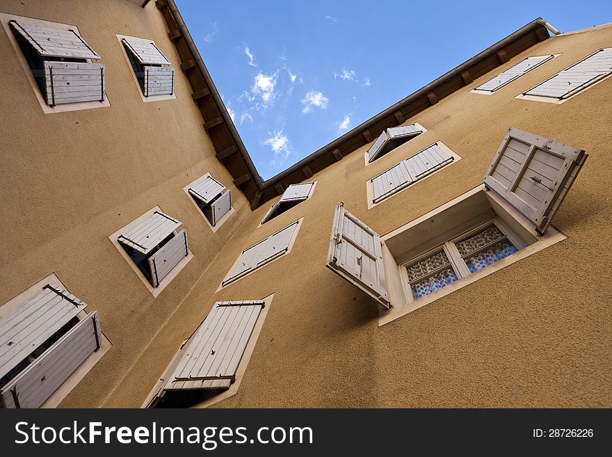 Two orange plastered walls in an angle covered with partially closed shutters, shot from a low angle. Two orange plastered walls in an angle covered with partially closed shutters, shot from a low angle.