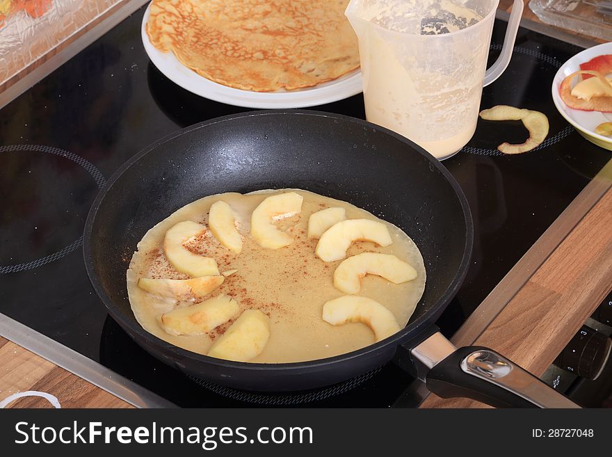 A nearly ready baked pancake with a circle of apple-slices to be baked together. A nearly ready baked pancake with a circle of apple-slices to be baked together