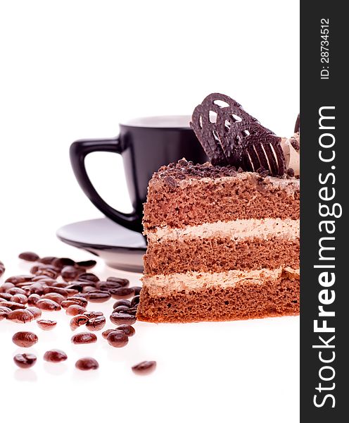 Piece of cake on the background of a black Cup with saucer and scattered grain coffee. Piece of cake on the background of a black Cup with saucer and scattered grain coffee
