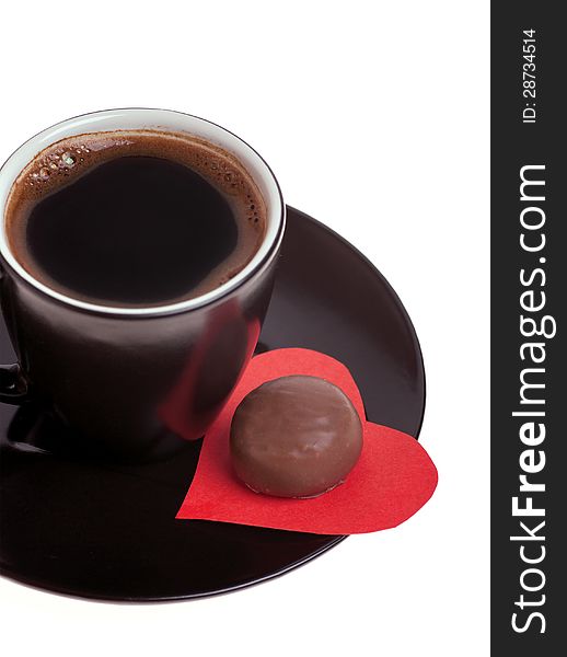 Round chocolate candy in the heart of red paper and black coffee on a white background. Round chocolate candy in the heart of red paper and black coffee on a white background