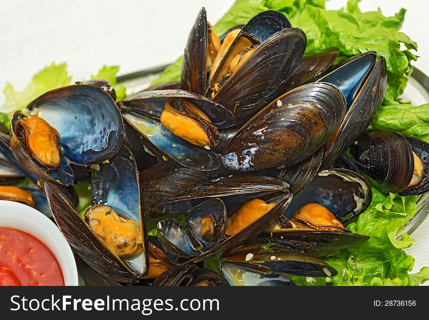 This is a plate of steamed mussels with lettuce leaves on a plate