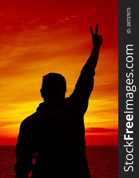Silhouette Image of Man Raising His Hand Showing Two Fingers