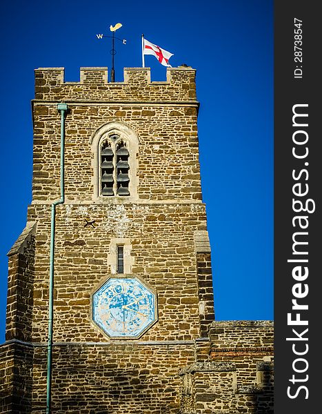 English church with St George Flag against blue sky