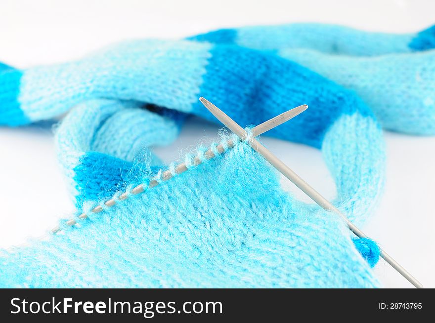 Needles knitting blue scarf on white background. Needles knitting blue scarf on white background