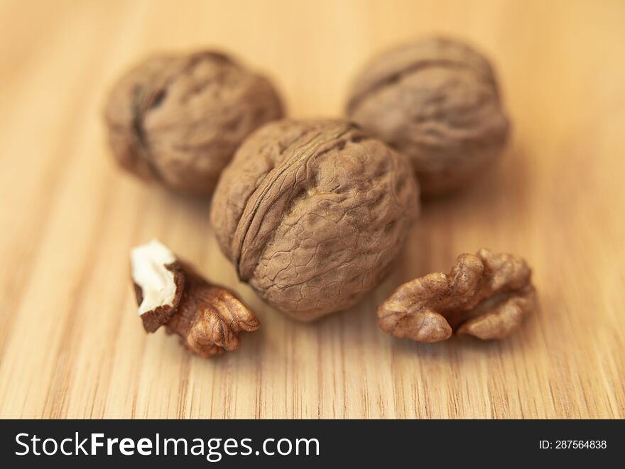Whole walnuts and peeled kernels on a wooden surface. Food and drink