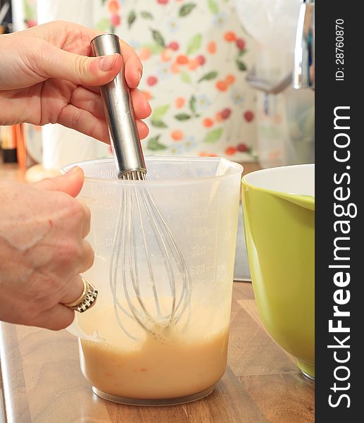 Milk and egg are mixed in a beaker with a whish, preparing the making of bread dumplings