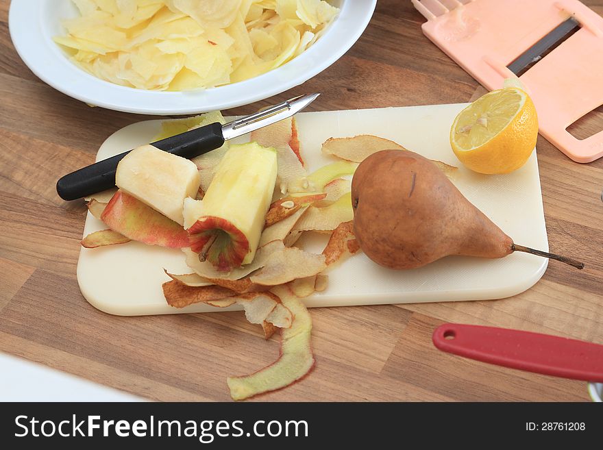 Rest of an apple which has been sliced, a pear which is wating to be slice, half a lemon, all ingredients to make a delicious strudel. In the background sliced apple and a grater. Rest of an apple which has been sliced, a pear which is wating to be slice, half a lemon, all ingredients to make a delicious strudel. In the background sliced apple and a grater