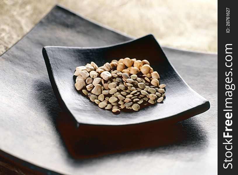 Assortment of dried legumes displayed on a contemporary black concave plate on a table