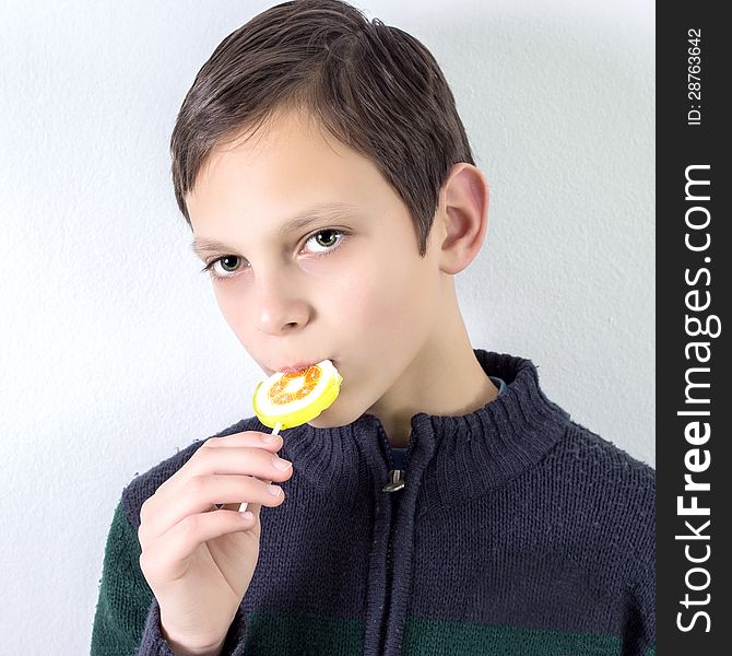 Schoolboy with lollipop over white wall,it is not