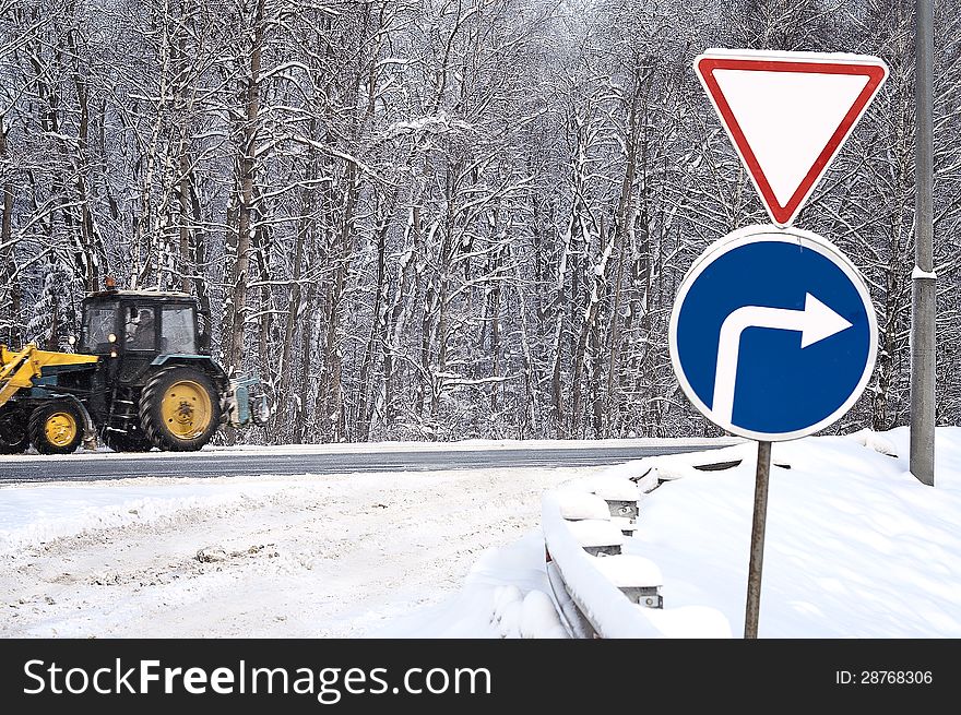 Give a way sign and tractor cleaning snow