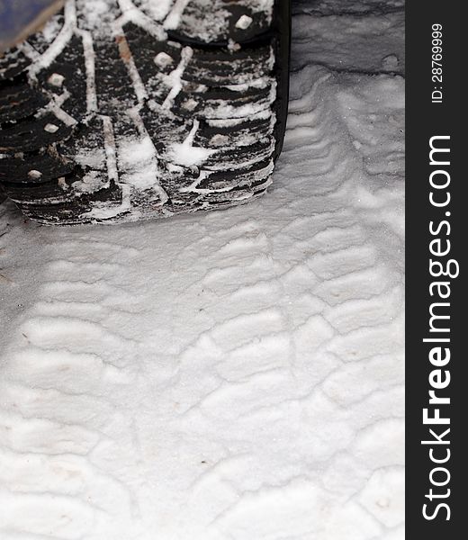 Winter tire tracks in snow, closeup, focus on tire