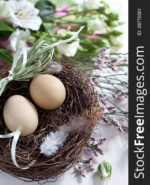 Easter basket with easter eggs and flowers on wooden background