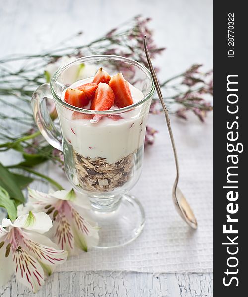 Muesli with yogurt ant strawberries on wooden background