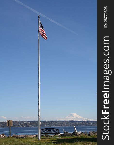 Point Robinson American Flag on Vashon Island with contrail in the blue sky and Mt Rainier in distance. Point Robinson American Flag on Vashon Island with contrail in the blue sky and Mt Rainier in distance.