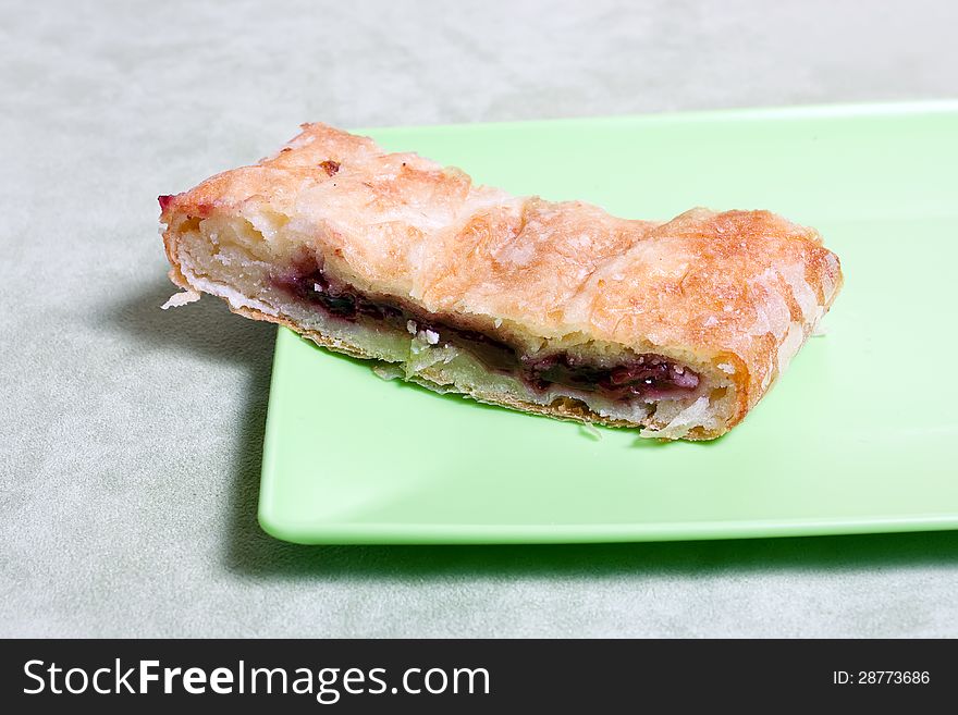 Homemade strudel with cherry on a green plate. Homemade strudel with cherry on a green plate