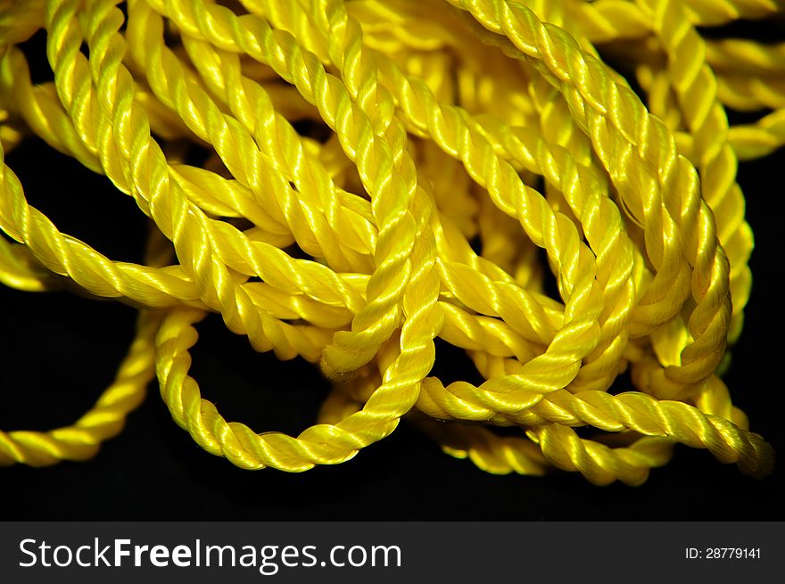 Black Background having yellow rope with multiple folds. Black Background having yellow rope with multiple folds