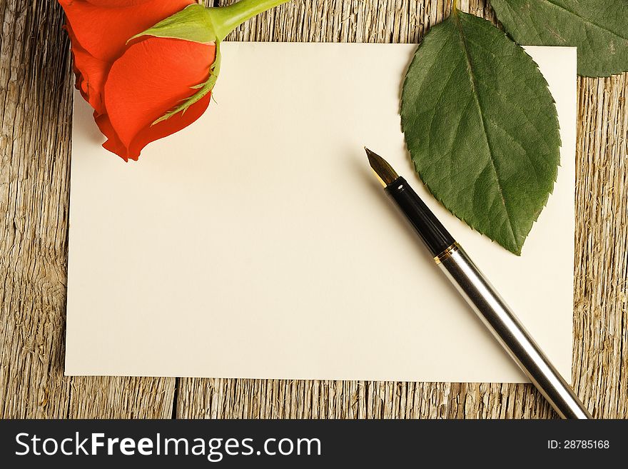 Blank card and pen near red rose on wooden background. Blank card and pen near red rose on wooden background