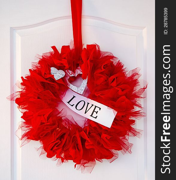 Valentine's red love garland with hearts hanging on a white door