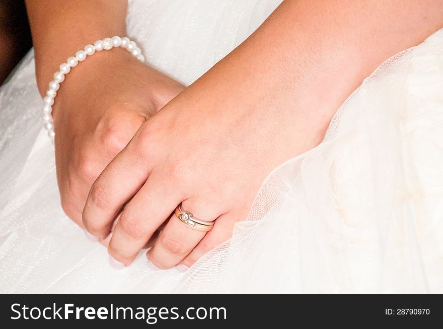 Hands of a young bride at the ceremony on the background of a white dress
