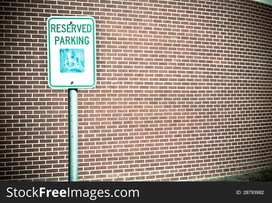 Reserved Handicap Parking sign in front of brick wall